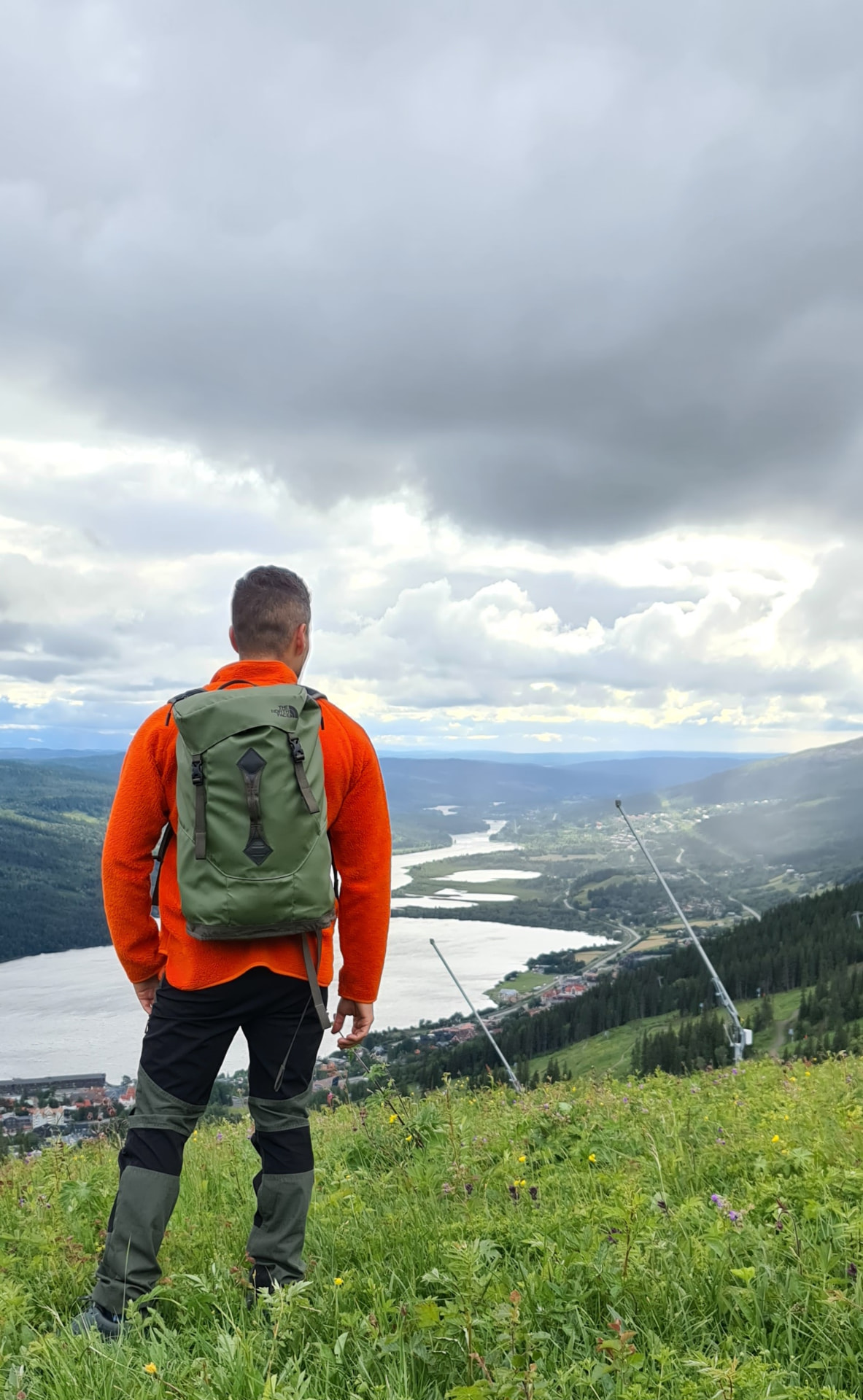 Hernán i orange tröja och ryggsäck blickar ut över fjällandskapet